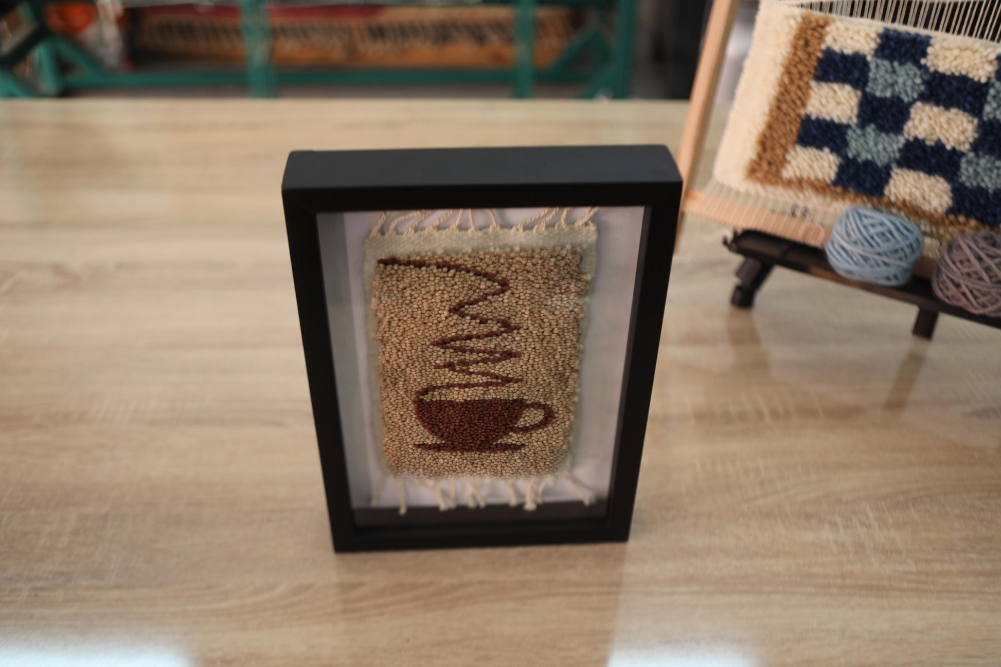 Hand-knotted Moroccan rug wall art (25x31 cm) featuring a cozy coffee cup design. A framed wool tapestry perfect for kitchens, cafés, or minimalist spaces.
