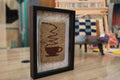 Hand-knotted Moroccan rug wall art (25x31 cm) featuring a cozy coffee cup design. A framed wool tapestry perfect for kitchens, cafés, or minimalist spaces.
