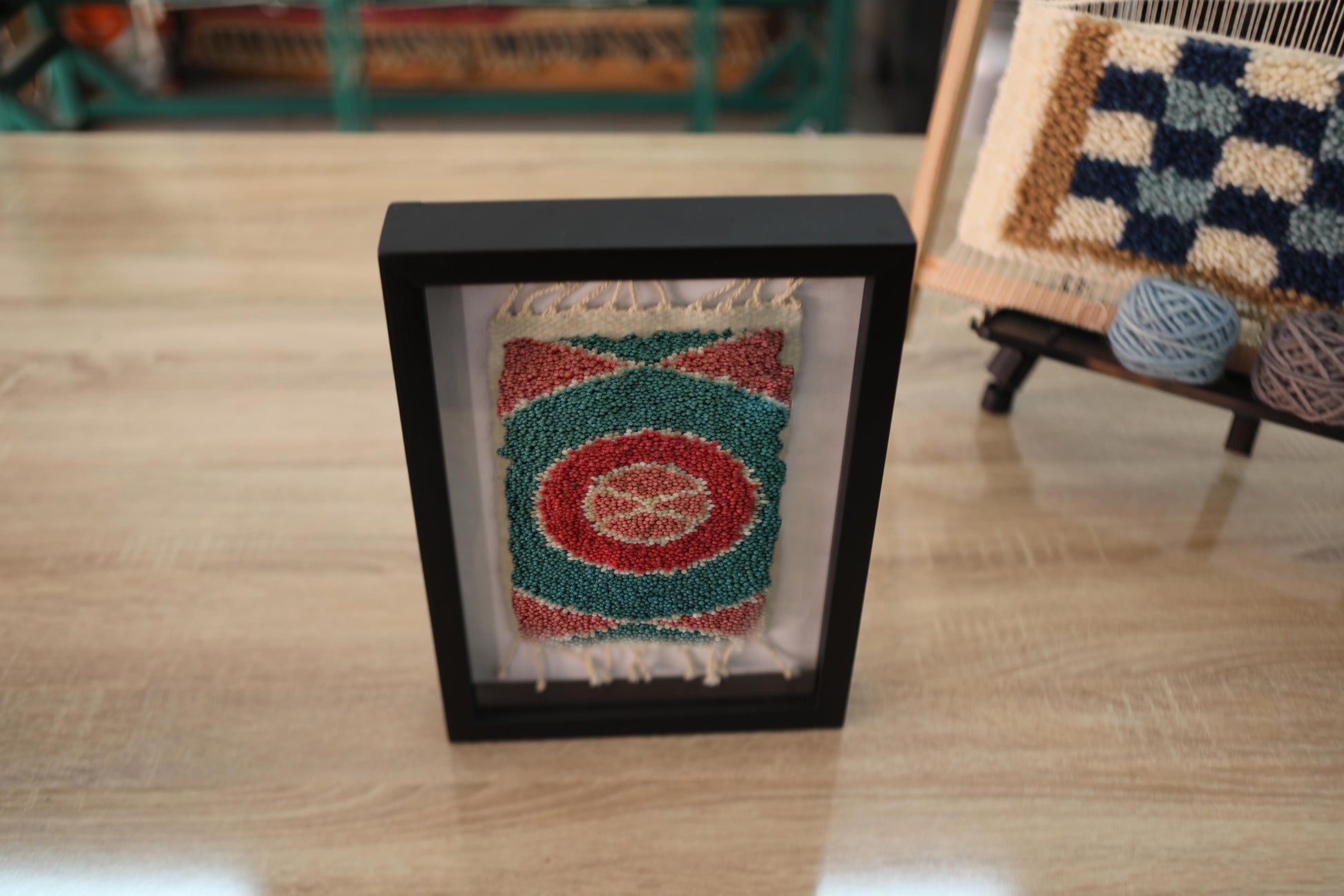 moroccan rug, circular wool rug art, hand-knotted framed tapestry, green red spiral rug, framed moroccan textile, miniature rug wall hanging, artisan moroccan decor, target motif rug, knot by knot rug weaving
