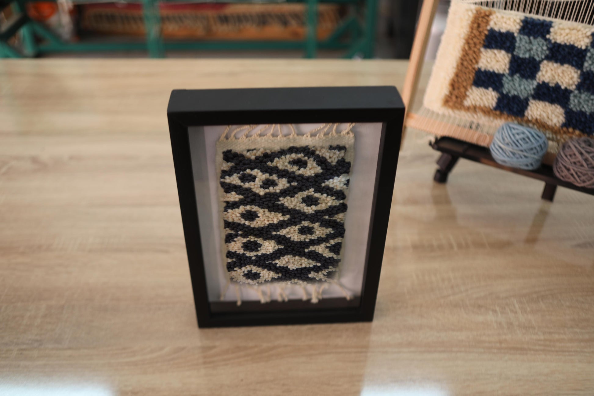 moroccan rug, eye pattern rug, beige and black wool, hand-knotted rug, framed mini rug wall art, traditional moroccan design, knot by knot weaving, artisan textile wall decor, wool wall hanging, berber rug art
