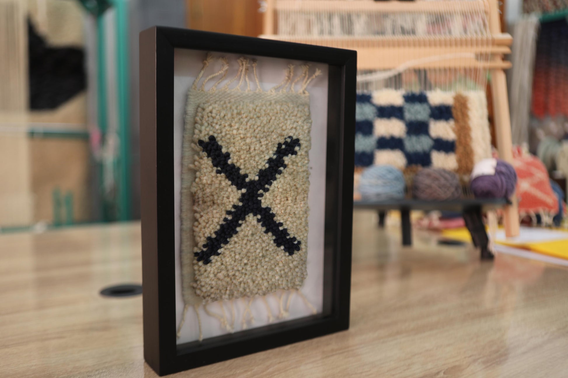 moroccan rug, x pattern rug wall art, framed wool wall hanging, hand-knotted mini rug, boho wall decor, black and beige wool tapestry, knot by knot weaving, artisan moroccan textile, tribal wall art, framed bohemian rug
