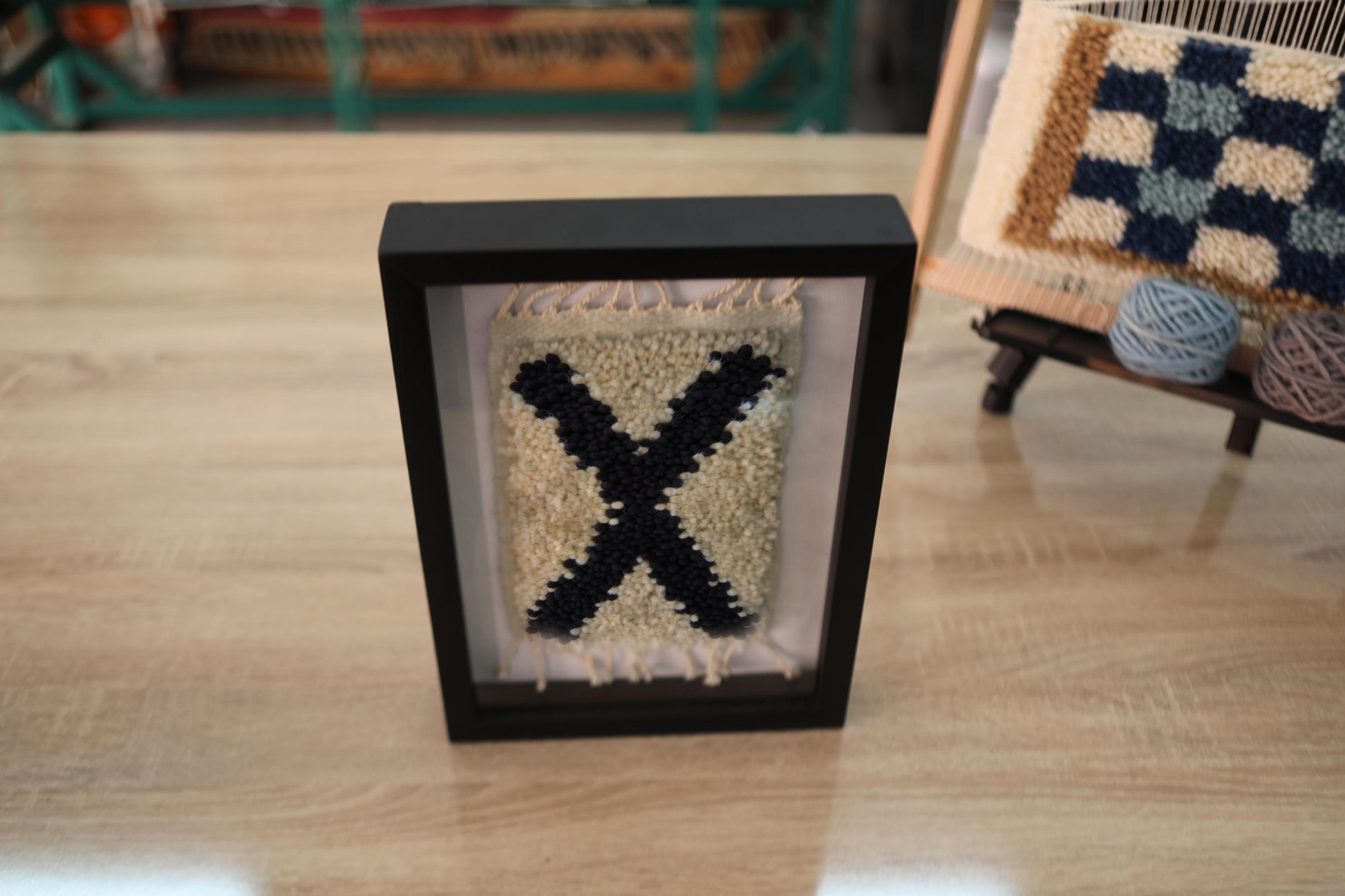 moroccan rug wall art, black x rug, framed wool wall hanging, boho wall decor, handmade moroccan textile, hand-knotted wall art, knot by knot weaving, tribal rug decor, small framed rug, artisan moroccan wall art
