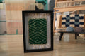 moroccan rug wall art, framed wool rug, hand-knotted moroccan textile, green tribal rug pattern, geometric maze rug design, boho wall decor, mini moroccan carpet art, 25x31 cm rug frame, artisanal wall hanging, knot by knot textile
