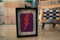 moroccan rug wall art, orange lightning bolt textile, framed wool tapestry, hand-knotted mini rug, purple wall decor, lightning strike rug art, wool knot by knot wall hanging, bold bohemian lightning art
