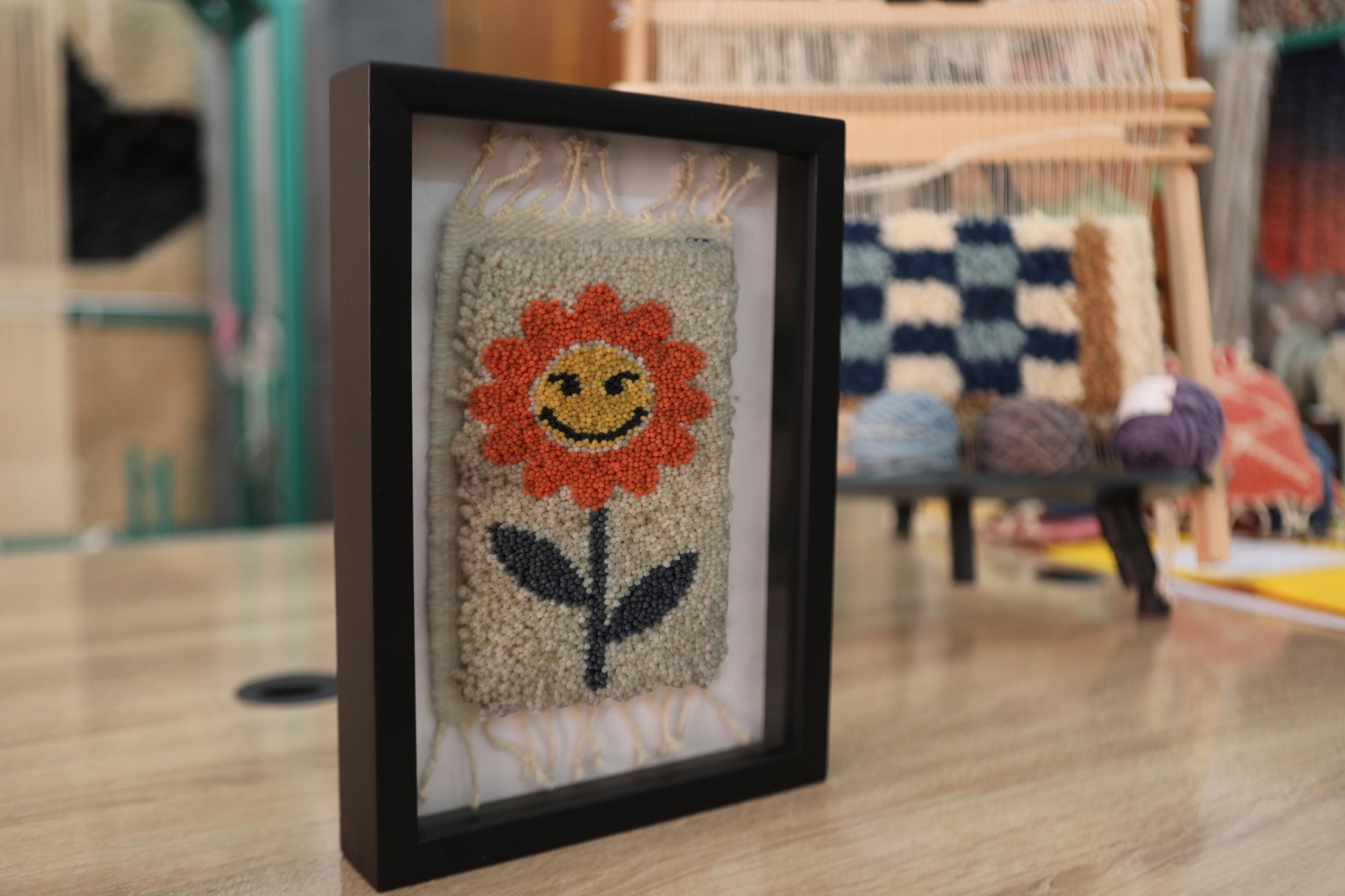 orange flower rug, moroccan rug wall art, hand-knotted wool tapestry, smiling flower textile, framed wool wall decor, mini moroccan rug, boho wool wall hanging, cheerful flower rug art, 25x31 cm framed textile, knot by knot rug design
