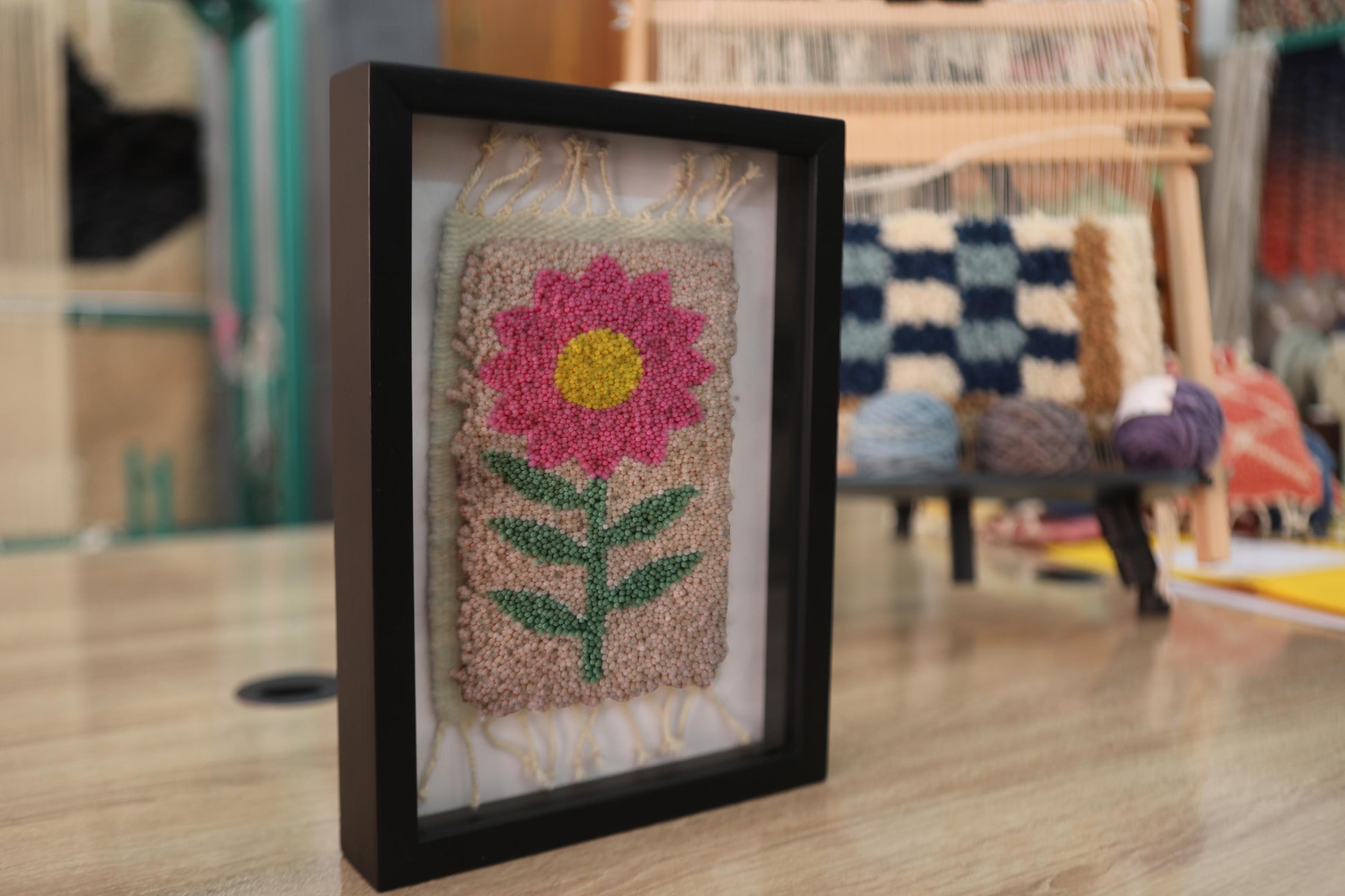 pink flower rug, moroccan rug wall art, hand-knotted wool textile, framed mini rug, boho flower wall decor, cheerful wool wall art, handmade pink flower rug, 25x31 cm wool tapestry, knot by knot rug art, smiling floral rug design
