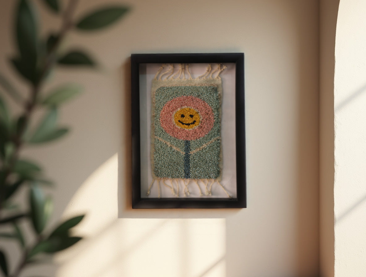 smiling flower rug, moroccan rug wall art, hand-knotted mini wool tapestry, happy flower textile decor, boho wall hanging, pink floral face rug, knot by knot moroccan rug, wool flower wall art, 25x31 cm framed rug, joyful flower textile art
